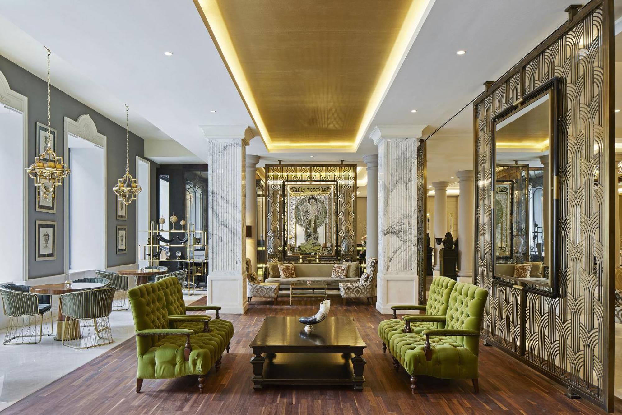 Titanic Gendarmenmarkt Berlin Extérieur photo The photo depicts a stylish and elegant interior space, likely a lobby or lounge area. It features tall ceilings with sophisticated lighting and a modern design aesthetic. There are two vibrant green chairs positioned around a dark wooden coffee tabl
